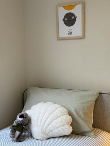 a stuffed dog laying on a bed with a towel at Scarborough Vacay - 3 bed house in Perth