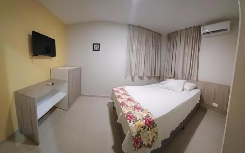 a hotel room with a bed and a television at FLATS VISTA MAR e FRENTE MAR NA PRAIA DOS CARNEIROS in Praia dos Carneiros