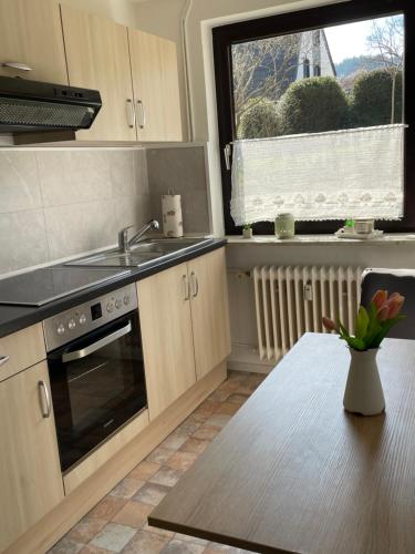 a kitchen with a sink and a table and a window at Ferienwohnung Appartement am Wildpark Bad Harzburg in Bad Harzburg