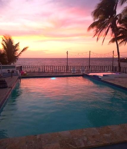 a swimming pool with a view of the ocean at sunset at Ventana Va102a at Arecibo 681 Ocean Drive in Arecibo