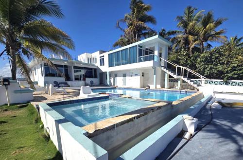 a large white house with a swimming pool at Ventana Va102a at Arecibo 681 Ocean Drive in Arecibo