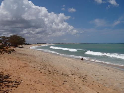 a sandy beach with people in the water at Pousada Casa Do Cocotier in São Miguel do Gostoso