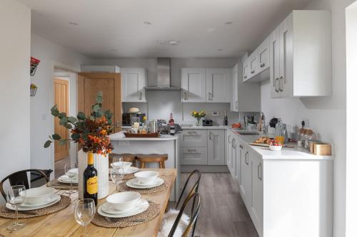 a kitchen with white cabinets and a table with chairs at Rowan Cottage-Ebrington in Ebrington