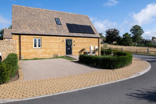 a brick house with solar panels on the roof at Rowan Cottage-Ebrington in Ebrington