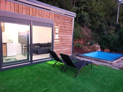 een achtertuin met een zwembad en stoelen op het gras bij Wood & Chill House in Sarajevo