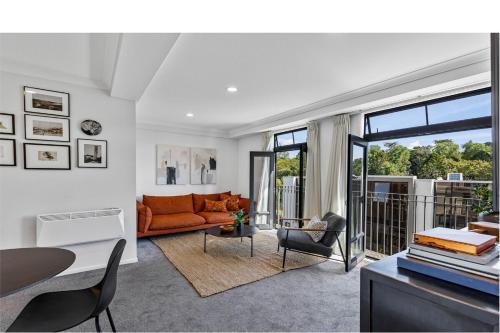 a living room with an orange couch and a table at Stonemasons Quarters Stylish apartment with carpark in Auckland