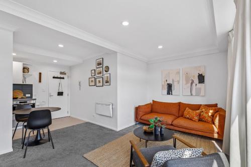 a living room with an orange couch and a table at Stonemasons Quarters Stylish apartment with carpark in Auckland