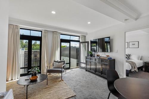 a living room with a bed and a table and chairs at Stonemasons Quarters Stylish apartment with carpark in Auckland