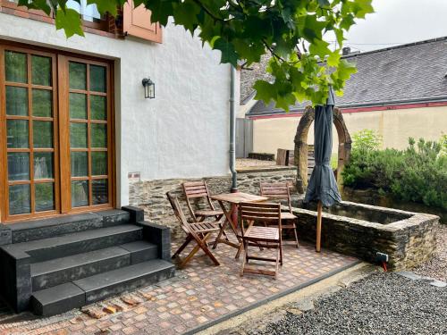 a patio with a table and chairs and an umbrella at Mosel Winzerhaus an der Lieser - Sonnenterrasse, Weinberge & Nähe Bernkastel-Kues in Maring-Noviand