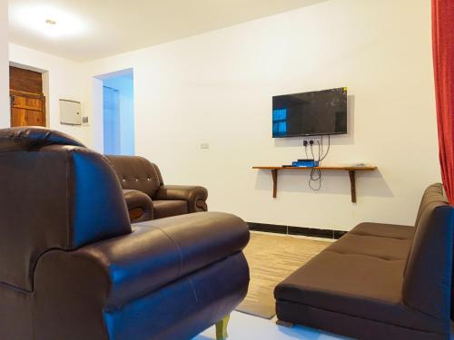 a living room with couches and a flat screen tv at Spacious Beachfront Condo -AC - WiFi, Uroa Escape Zanzibar in Uroa