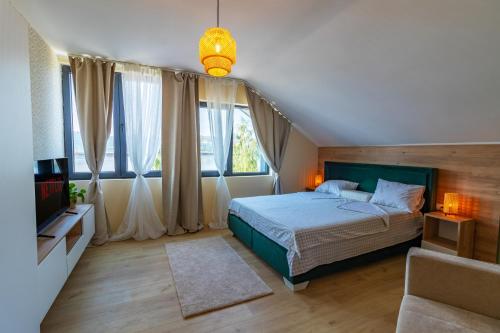 a bedroom with a bed and a tv and windows at Ramonda in Veliko Gradište