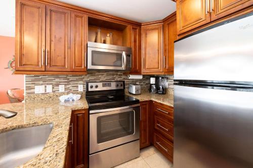 a kitchen with wooden cabinets and a stainless steel refrigerator at Morritt's Tortuga Club 1 BR LUXE Condo Sleeps 4 in Sand Bluff
