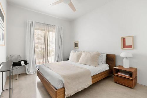 a white bedroom with a bed and a window at Boulder Surrounded Escape- ANOTHERdeserthouse in Yucca Valley