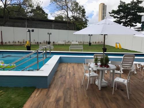 a table with an umbrella next to a pool at Flats Mobiliados Zona Norte, Casa Forte e Recife in Recife