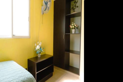 a bedroom with a bed and a shelf with flowers at Hermosa casa residencial alberca propia climatizada in Cuautla Morelos