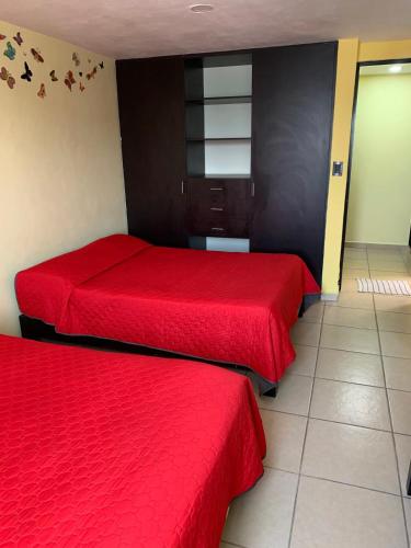 two beds in a room with red sheets at Hermosa casa residencial alberca propia climatizada in Cuautla Morelos