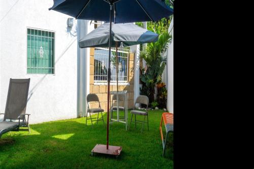 a table and chairs and an umbrella in the grass at Hermosa casa residencial alberca propia climatizada in Cuautla Morelos