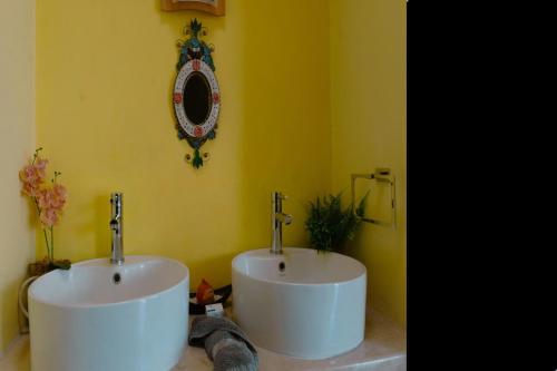 a bathroom with a white sink and a yellow wall at Hermosa casa residencial alberca propia climatizada in Cuautla Morelos