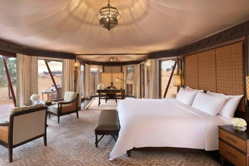 a bedroom with a large bed and a living room at The Ritz-Carlton Ras Al Khaimah, Al Wadi Desert in Ras al Khaimah
