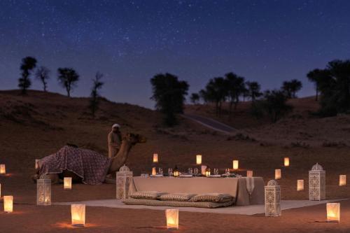 a woman taking a picture of a table in the desert at night at The Ritz-Carlton Ras Al Khaimah, Al Wadi Desert in Ras al Khaimah