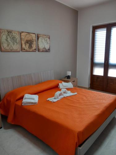 Un dormitorio con una cama naranja con toallas. en Il Rifugio del Salento, en Sava