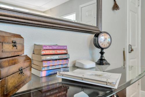 a stack of books on a glass table next to a mirror at Spacious House with big backyard in N. Hyde Park / Close to Downtown in Tampa