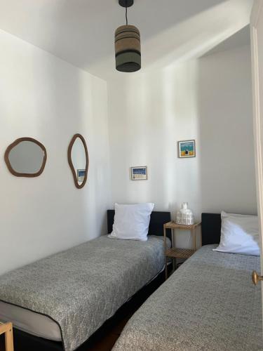 een slaapkamer met twee bedden en een spiegel aan de muur bij Départ du Marin à la Cotinière in Saint-Pierre-dʼOléron