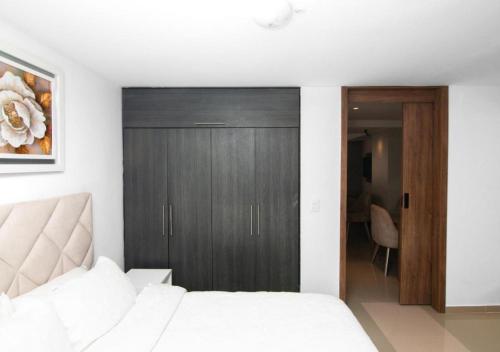 a bedroom with a white bed and a wooden closet at Trento Class 1001 Elegante y Confortable con Parqueadero in Bucaramanga