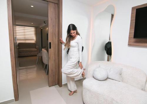 a woman in a white dress standing next to a couch at Trento Class 1001 Elegante y Confortable con Parqueadero in Bucaramanga