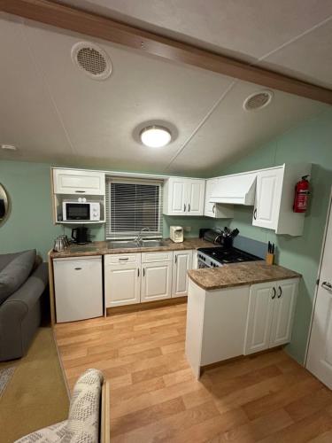 a kitchen with white cabinets and a couch in a room at Slaley Forest Hexham Caravan Retreat Pet Friendly - sleeps 6 in Slaley