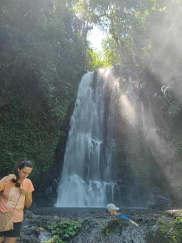 a woman standing in front of a waterfall at Laras Homestay Munduk in Munduk