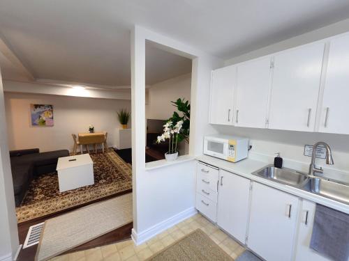 a kitchen with white cabinets and a living room at Byward Market Downtown Guesthouse in Ottawa