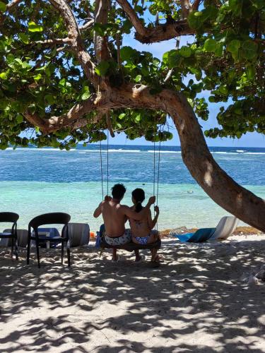 two people sitting in a swing on the beach at Hotel xahuayxol in Mahahual