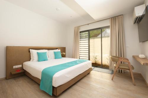 a bedroom with a bed and a desk and a window at Moorea Beach Villas in Haapiti