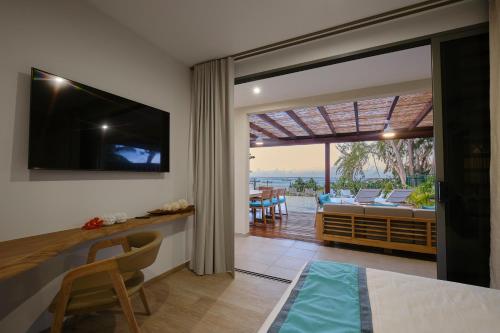 a living room with a television and a dining room at Moorea Beach Villas in Haapiti
