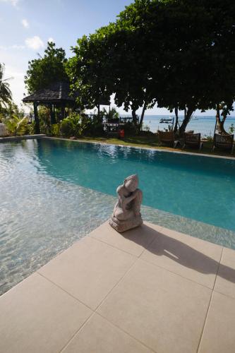a statue sitting next to a swimming pool at Moorea Beach Villas in Haapiti