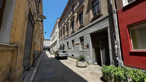 an alley with a car parked next to buildings at Spacious apartment in the city centre in Sarajevo