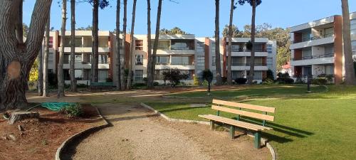 a wooden bench sitting in a park next to a building at Lindo y cómodo departamento en Algarrobo, Chile in Algarrobo