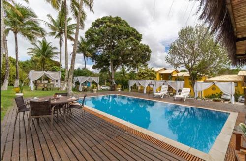 una piscina en un complejo con mesa y sillas en Studio 64 - Trancoso, en Porto Seguro