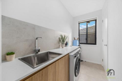 una cucina con lavello e lavatrice di Austral 5 bedroom, 2 storey detached house a Austral