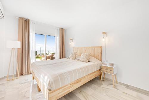 a white bedroom with a bed and a large window at The loving hummingbird in Mijas Costa