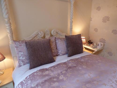 a bedroom with a bed with purple sheets and pillows at Douglas Park Guest House in Dunoon
