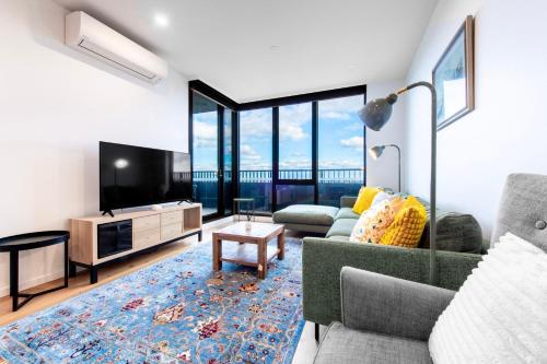 a living room with a flat screen tv and a couch at Elevated Escape - 2BR w Gym & Rooftop Spa in Melbourne