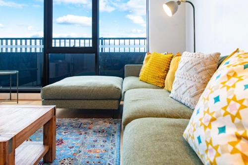 a living room with a couch and large windows at Elevated Escape - 2BR w Gym & Rooftop Spa in Melbourne