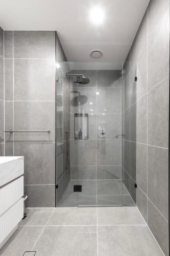 a shower with a glass door in a bathroom at Elevated Escape - 2BR w Gym & Rooftop Spa in Melbourne