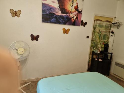 a room with butterflies on the wall and a fan at Chambre avec salle de bain in Penta-di-Casinca