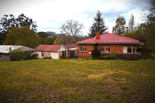 una casa de ladrillo con techo rojo en un patio en Hartwood Farm in the Huon Valley, en Geeveston