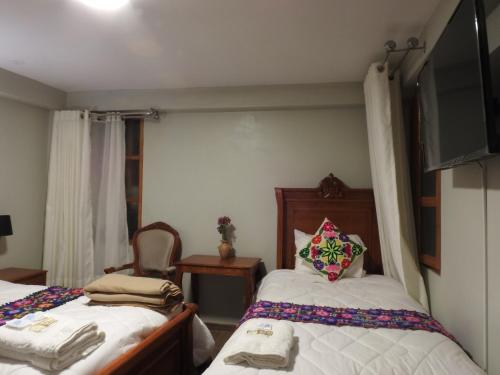 a bedroom with two beds and a flat screen tv at Rumi Wasi Inn Ollantaytambo in Ollantaytambo