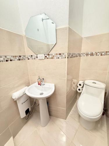 a bathroom with a toilet and a sink and a mirror at Yellow House in Quepos