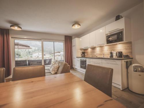 a kitchen with a wooden table and a large window at Lodge Amanda-Elise in Vorderkrimml